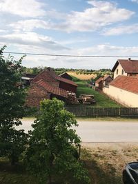 Houses by trees against sky