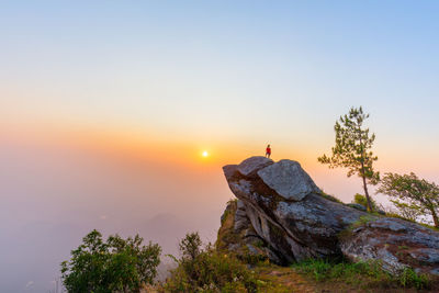 Woman of rock against sky during sunset