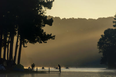 Silhouette people on beach against sky during sunset