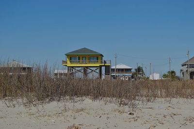 House on field by building against clear sky