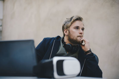 Thoughtful computer programmer looking away while sitting at desk in office