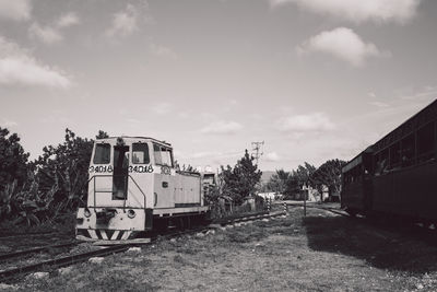 Train on railroad track amidst field against sky