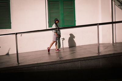 Woman wearing hat walking against building