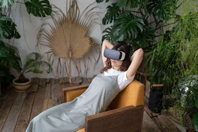 Amazed young woman using vr in home garden, resting in relaxing virtual environment. cyberspace.