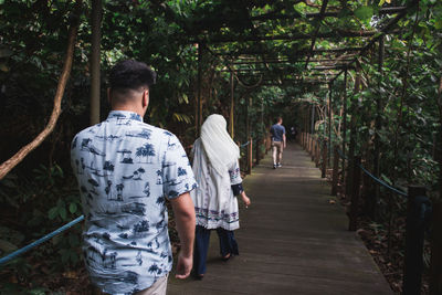 Rear view of people walking on footpath in forest