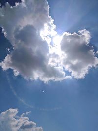 Low angle view of sunlight streaming through clouds