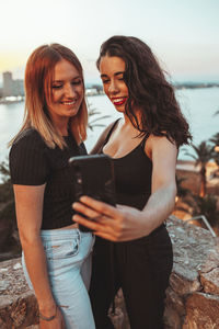 Young woman using phone while standing outdoors