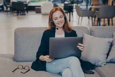 Young woman using laptop while sitting on sofa at home