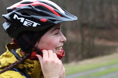 Close-up of smiling young woman wearing cycling helmet