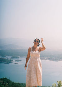 Young woman standing by sea against sky