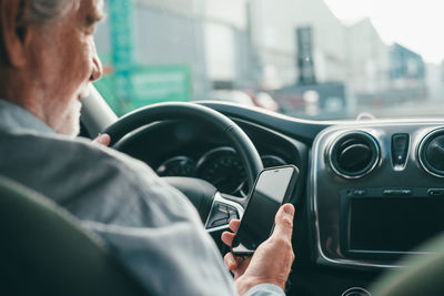 Close-up of senior man using phone while driving