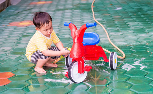 High angle view of boy washing tricycle outdoors