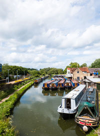 Boats moored on river by buildings against sky