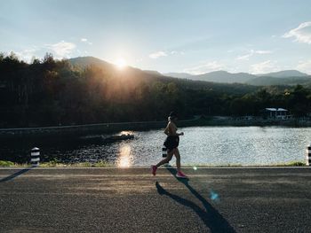 Girl running on lake against sky