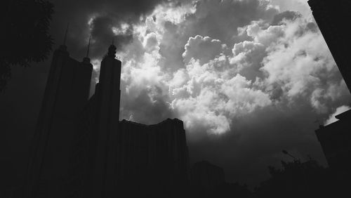 Low angle view of silhouette buildings against cloudy sky