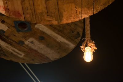 Low angle view of illuminated light bulb hanging on ceiling