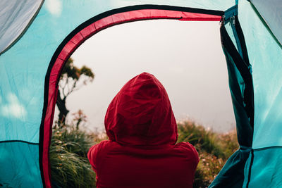 Rear view of person relaxing in tent on field