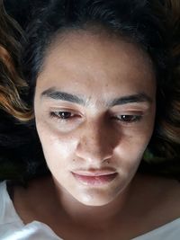 Directly above shot of thoughtful young woman lying on bed