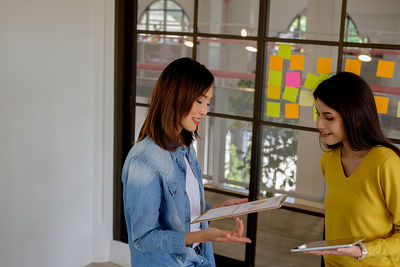 High angle view of colleagues discussing data while standing by window in office