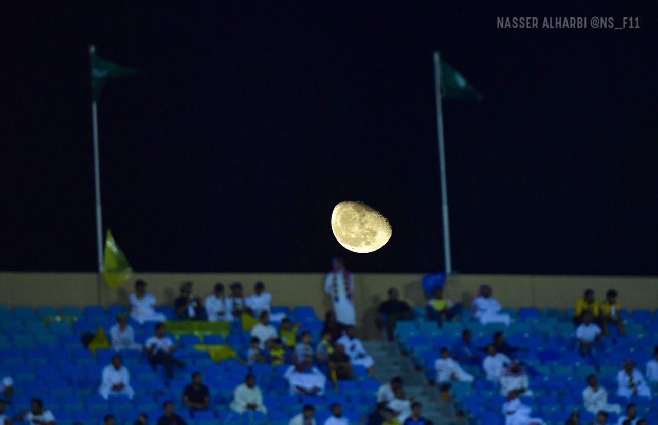 GROUP OF PEOPLE AT SOCCER FIELD AGAINST MOON