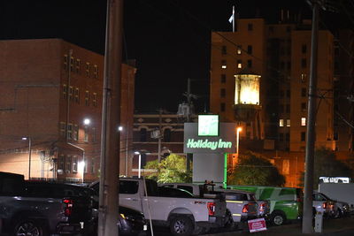 Cars on street against illuminated buildings in city at night