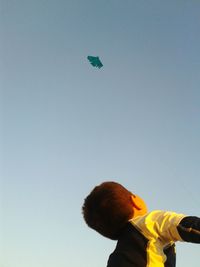 Low angle view of boy looking at kite in sky