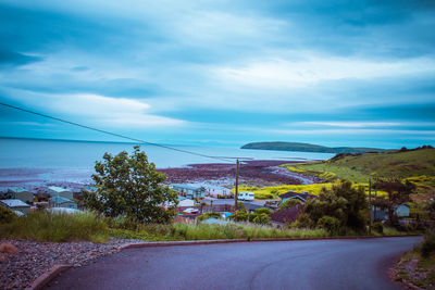 Empty road by trees and plants against sky