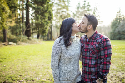 Confident, attractive couple kissing outdoors.