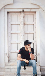 Full length of young man sitting in front of building