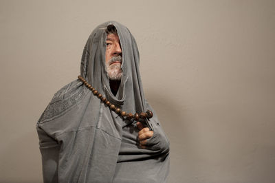 Portrait of man holding cross against gray background