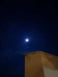 Low angle view of illuminated moon against blue sky