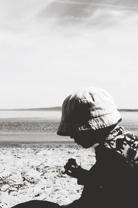 Boy wearing hat at beach against sky