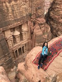 Full length of woman sitting on rock