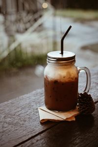 Chocolate drink in container by pine cone on table