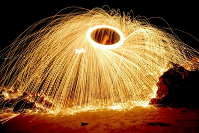 Man standing by wire wool against sky at night