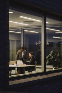 Mature businesswoman discussing with female colleague in office at night