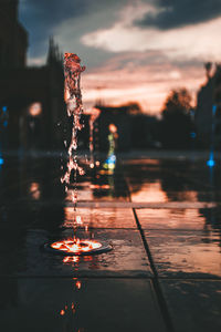 Close-up of illuminated fountain in city during sunset