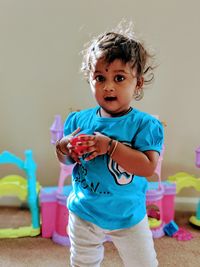 Portrait of cute girl with toy standing at home