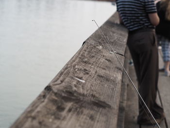 Midsection of man standing by retaining wall over lake