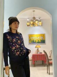 Portrait of young woman standing against wall