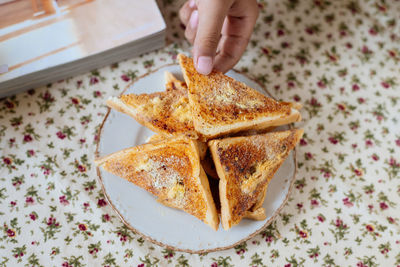 Close-up of person hand holding toasted bread on table