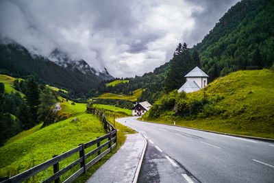 Road amidst trees and mountains against sky