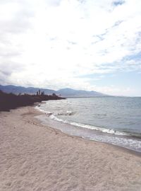 Scenic view of beach against cloudy sky