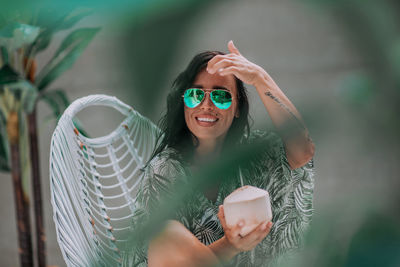 Portrait of a smiling young woman holding sunglasses