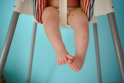 The child eats in a child seat, his legs are visible