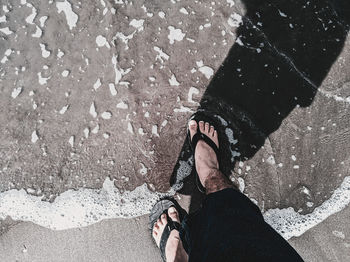 Low section of man standing on road in rain