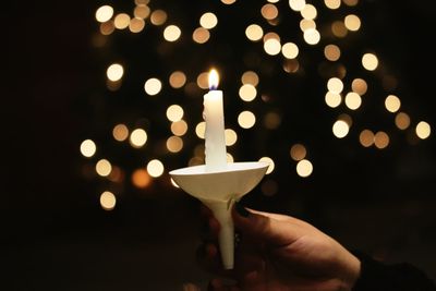 Close-up of hand holding illuminated candle