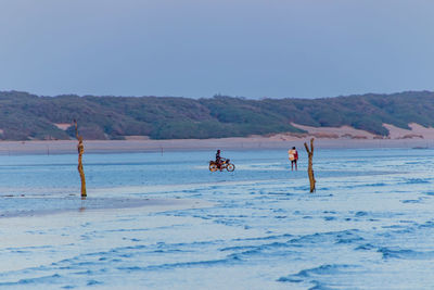 People on beach against clear sky