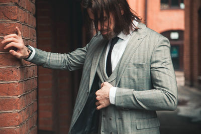 Midsection of man standing against wall