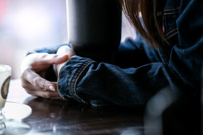 Midsection of woman sitting at table in cafe